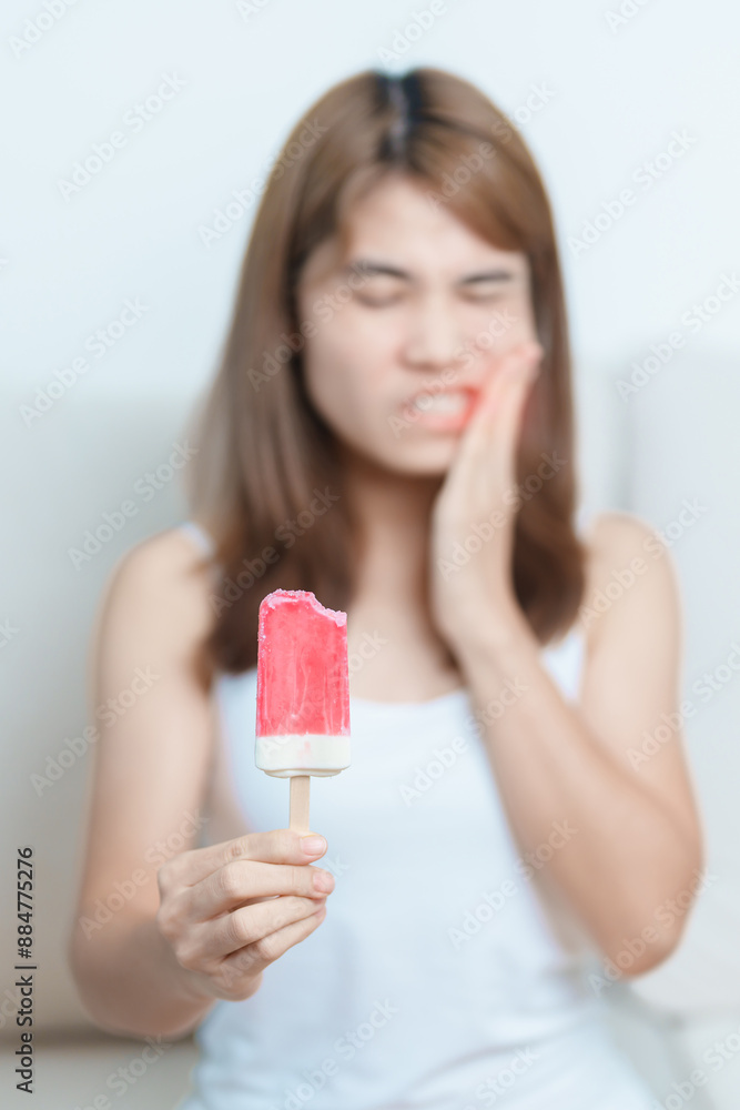 Teeth Sensitive to Cold concept. woman hold Ice cream and having toothache and pain after eat. Tooth Decay or Gum Disease, Grinding Teeth and Stress, Exposed Nerve Roots, Crack and Receding Gums Teeth Sensitive to Cold concept. woman hold Ice cream and having toothache and pain after eat. Tooth Decay or Gum Disease, Grinding Teeth and Stress, Exposed Nerve Roots, Crack and Receding Gums
