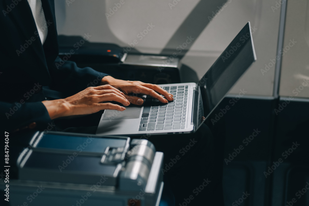 A successful asian businesswoman or female entrepreneur in formal suit in a plane sits in a business class's seat and uses a tablet computer during flight A successful asian businesswoman or female entrepreneur in formal suit in a plane sits in a business class's seat and uses a tablet computer during flight
