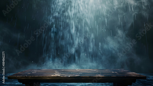 A wooden table is covered in rain and mist. The mist is coming from a waterfall, creating a serene and peaceful atmosphere © tracy