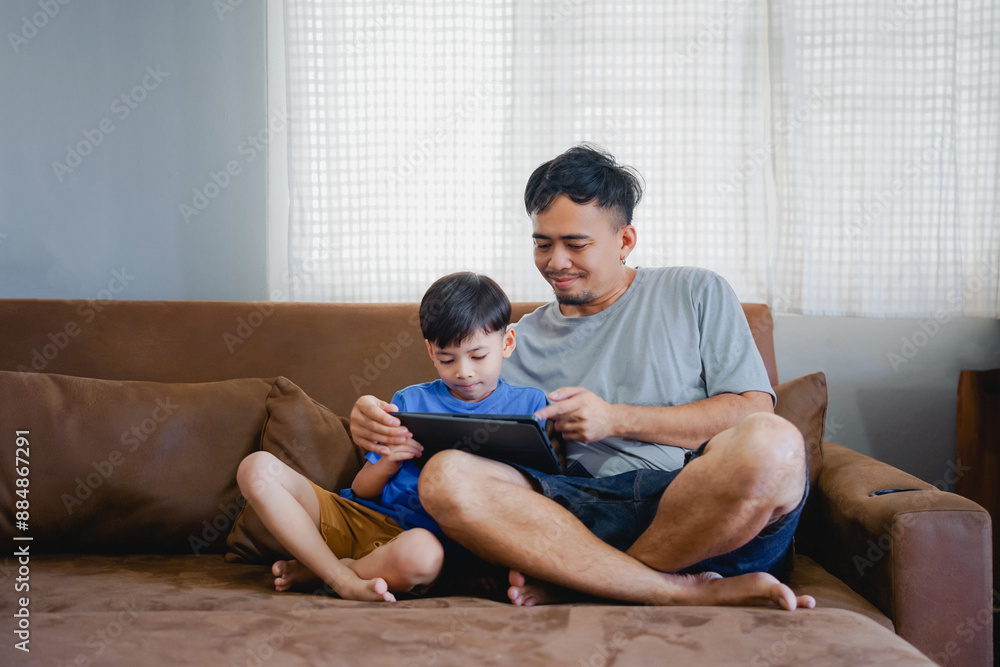 Father look son while he play video games or browse internet on tablet
Father look son while he play video games or browse internet on tablet