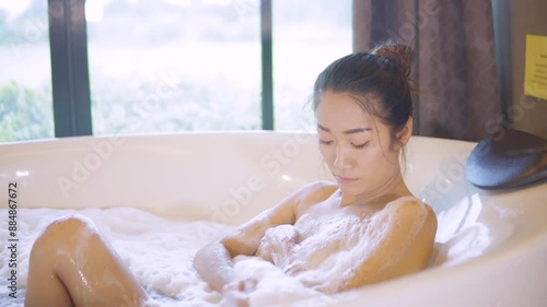 Sexy Asian girl taking a foam bath in the bathtub.