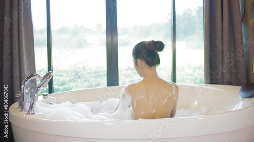 Sexy Asian girl taking a foam bath in the bathtub.