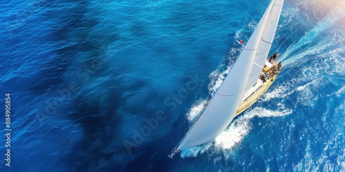 An aerial photo of a sailing yacht in the open sea, with the boat set against the clear blue ocean. Concept for ocean travel and adventure.