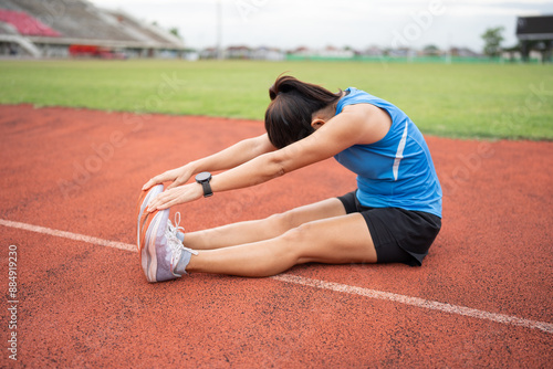 Happy Mature Asia woman runner stretching before run on racetrack and field  © chachamp