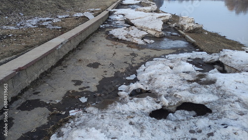 Ice floes on the sidewalk of the embankment after the spring flood on the river in Europe