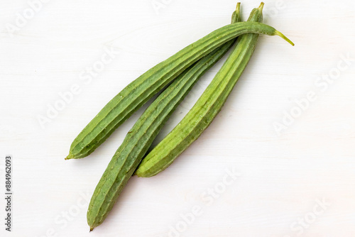 Fresh ridge gourds placed on a light wooden surface. It is also known as Jhinga, Chinese okra, Silk squash, and Turai. photo