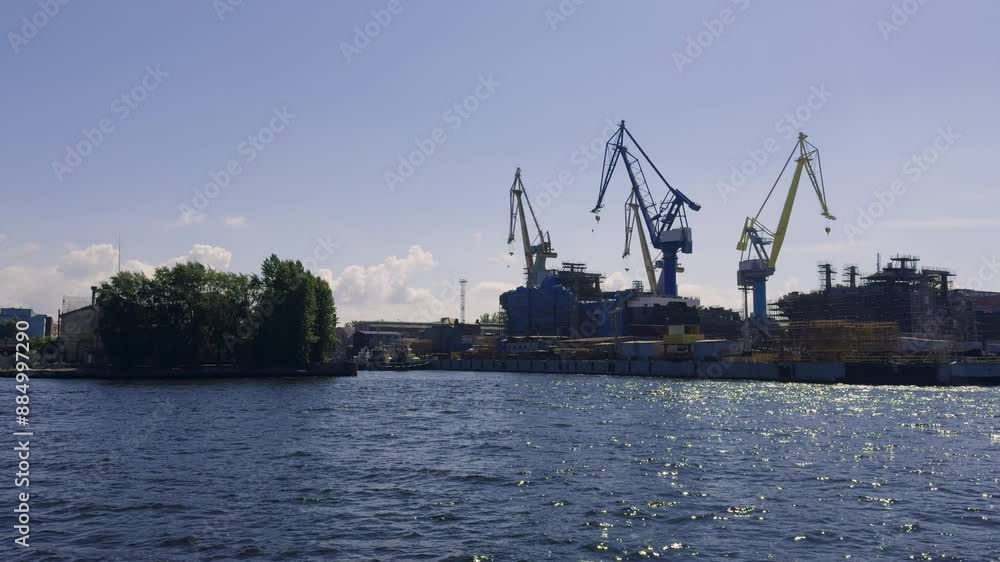 A bustling industrial harbor featuring cranes, warehouses, and various industrial equipment under a clear blue sky with scattered clouds, highlighting the busy maritime environment A bustling industrial harbor featuring cranes, warehouses, and various industrial equipment under a clear blue sky with scattered clouds, highlighting the busy maritime environment