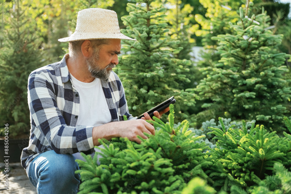 Using digital tablet, sitting. Senior gardener is at work at daytime Using digital tablet, sitting. Senior gardener is at work at daytime