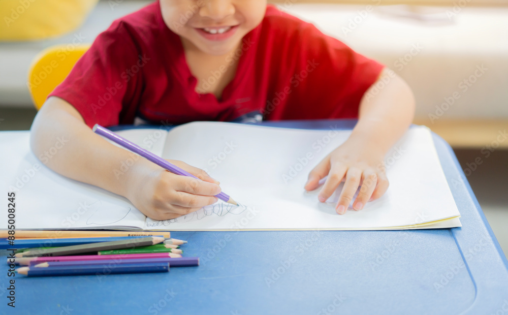 Cropped shot of cute happy little Asian boy painting with pencil and color on art book in room Cropped shot of cute happy little Asian boy painting with pencil and color on art book in room