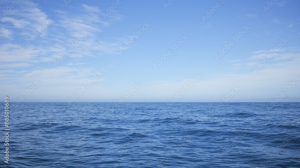 Serene view of the ocean under a clear blue sky with scattered clouds in New Zealand Serene view of the ocean under a clear blue sky with scattered clouds in New Zealand