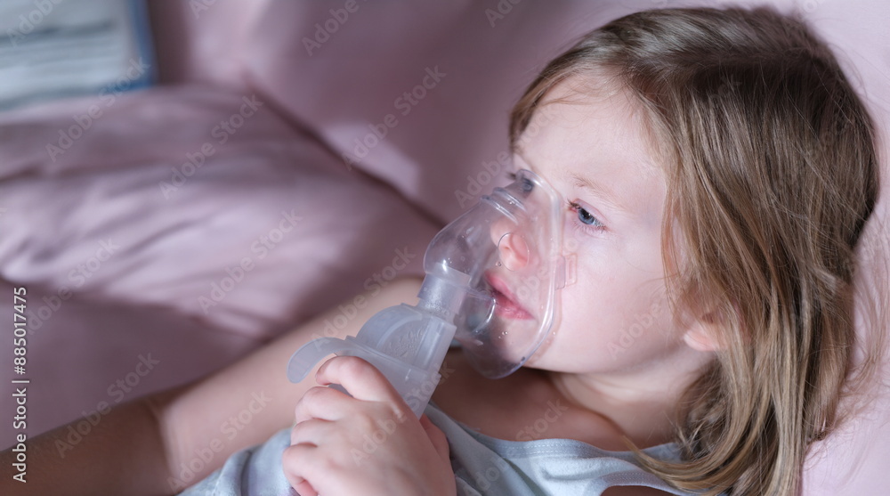 Portrait of sick little child in medical oxygen mask lying in bed. Labored breathing and lack of oxygen or inhalation concept Portrait of sick little child in medical oxygen mask lying in bed. Labored breathing and lack of oxygen or inhalation concept
