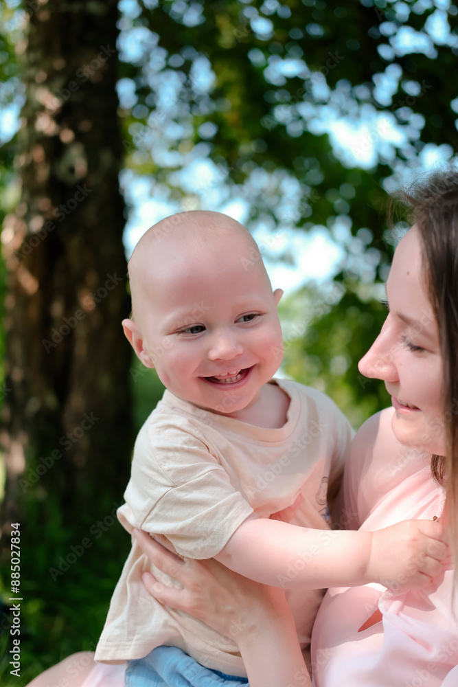 Happy mother and child hugging in summer park with love, smile and care or health development. Happy family concept. Portrait of human emotions. Advertising of children's products. Vertical image Happy mother and child hugging in summer park with love, smile and care or health development. Happy family concept. Portrait of human emotions. Advertising of children's products. Vertical image
