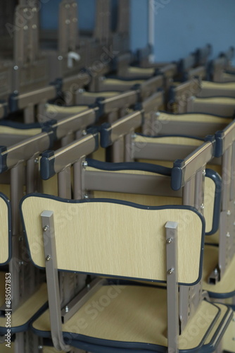 a series of beige-colored school desks with attached chairs, arranged in rows and columns.