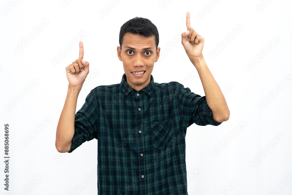 Asian man wearing a green checkered casual shirt pointing towards an empty space for advertising. Isolated white background. Asian man wearing a green checkered casual shirt pointing towards an empty space for advertising. Isolated white background.
