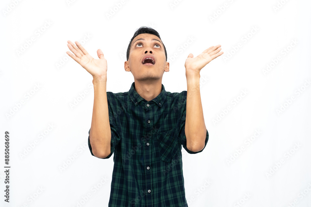 Asian man wearing a green checkered casual shirt pointing towards an empty space for advertising. Isolated white background. Asian man wearing a green checkered casual shirt pointing towards an empty space for advertising. Isolated white background.