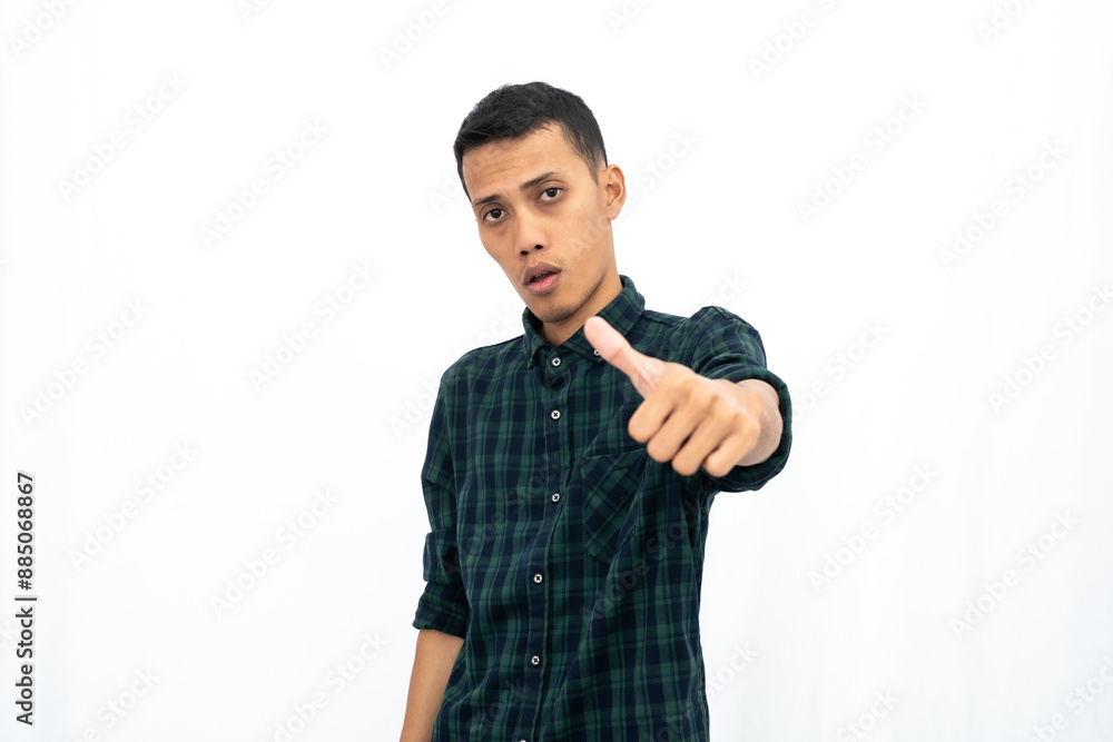 Asian man wearing a green checkered casual shirt stressed showing thumbs up that agree, okay, top. Isolated white background. Asian man wearing a green checkered casual shirt stressed showing thumbs up that agree, okay, top. Isolated white background.
