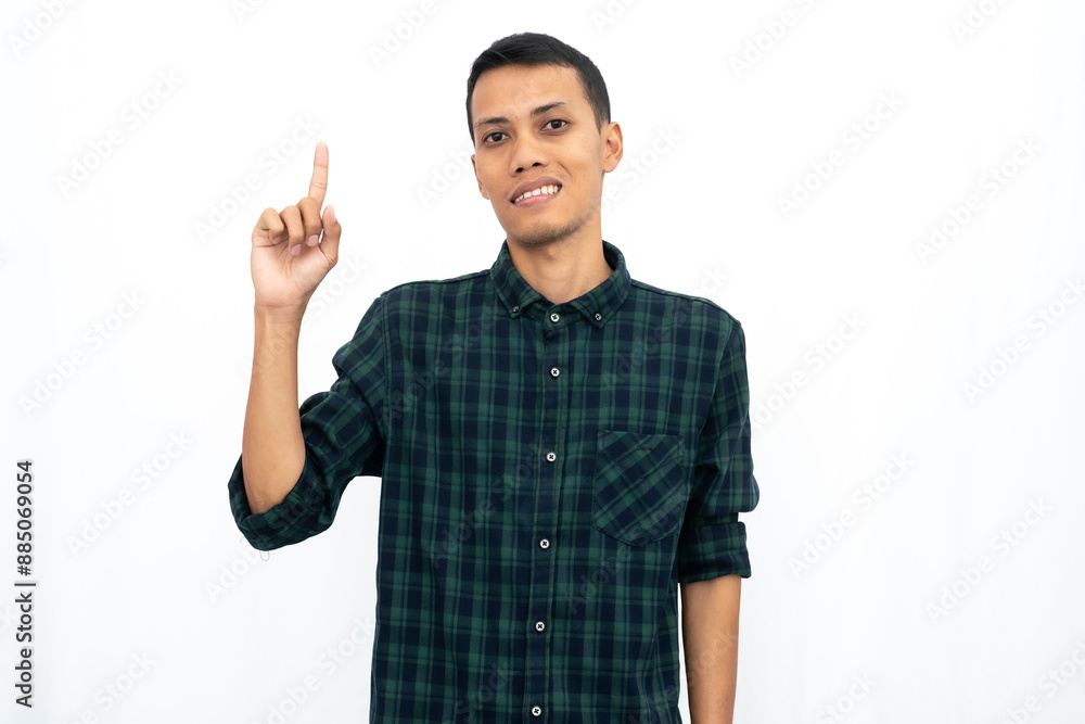 Asian man wearing a green checkered casual shirt pointing towards an empty space for advertising. Isolated white background. Asian man wearing a green checkered casual shirt pointing towards an empty space for advertising. Isolated white background.
