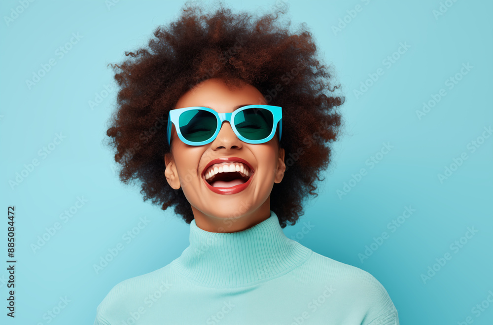 A woman with a bright smile and curly hair wearing stylish blue sunglasses against a turquoise background. Her joyful expression and vibrant look radiate positivity and energy A woman with a bright smile and curly hair wearing stylish blue sunglasses against a turquoise background. Her joyful expression and vibrant look radiate positivity and energy