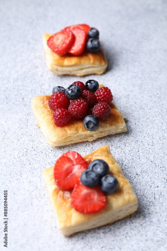 Tasty puff pastries with berries on light grey table Tasty puff pastries with berries on light grey table