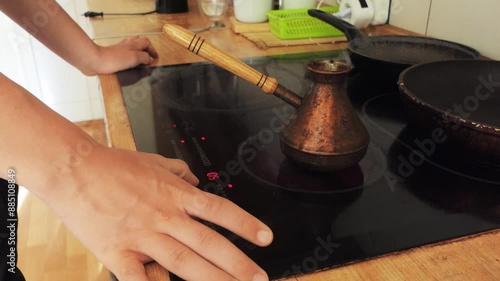 A teenager makes coffee using a Turk in the kitchen. photo