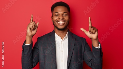 A man in a suit is pointing to the camera with a smile on his face. Concept of positivity and confidence. Funny cheerful smiling young african american business man