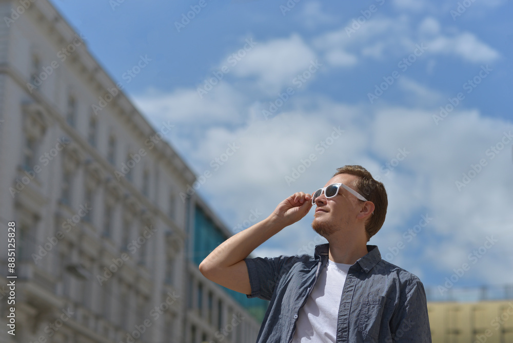 A man wearing sunglasses on the street in Vienna. The concept of hot sunny weather in the city. A man suffers from the heat A man wearing sunglasses on the street in Vienna. The concept of hot sunny weather in the city. A man suffers from the heat