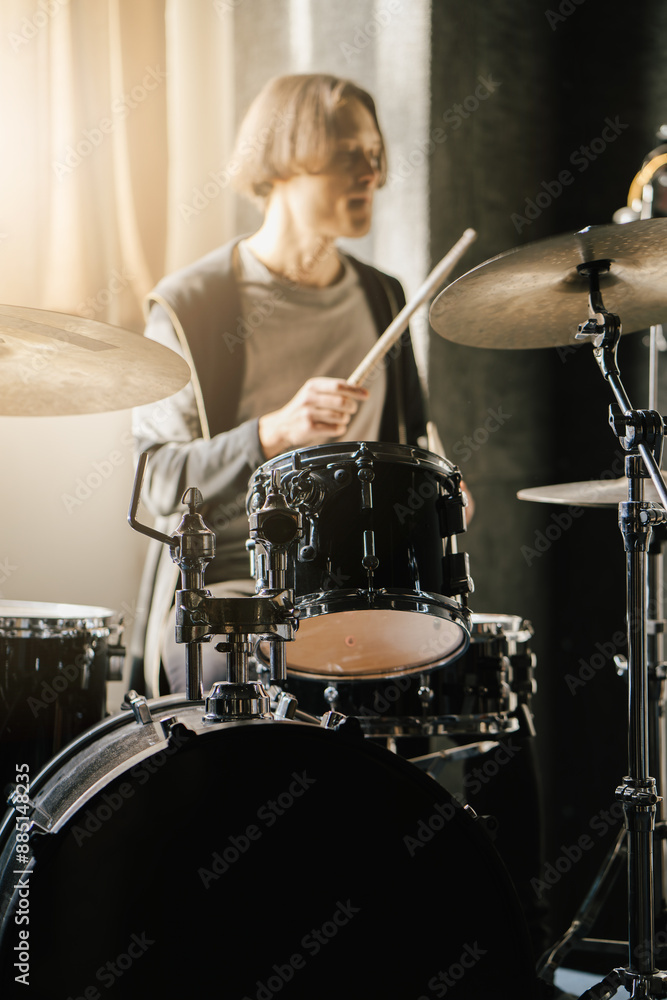 Fototapeta premium Young drummer playing drums in music studio, vibrant and energetic atmosphere, vertical