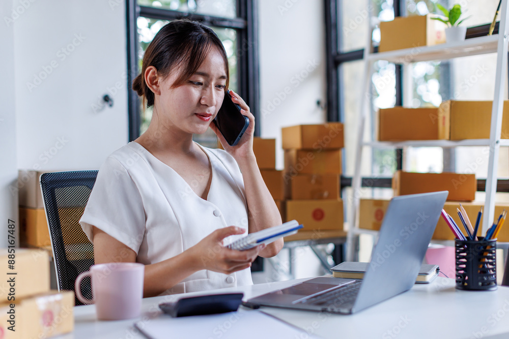 Obraz premium Young asia seller woman happy work on laptop busy cellphone call chat to customer at home office desk use digital tablet computer in SME online store social e-commerce sale page service web support. 