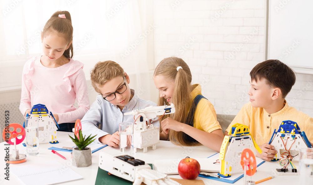 Four children, three boys and one girl, are working on building robots in a classroom setting. They are all focused on their tasks and seem to be enjoying themselves. The classroom is bright Four children, three boys and one girl, are working on building robots in a classroom setting. They are all focused on their tasks and seem to be enjoying themselves. The classroom is bright