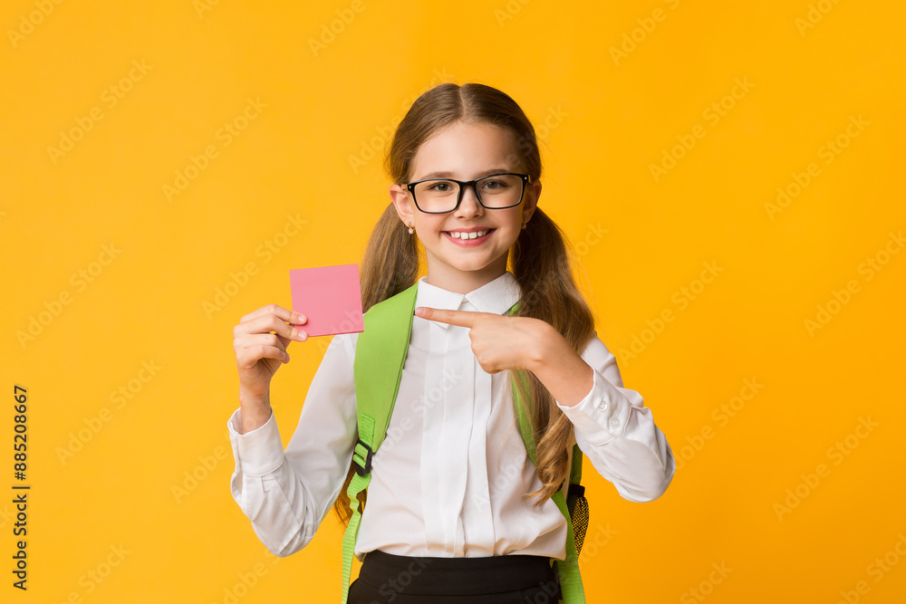 Take Notes. Schoolgirl Pointing Finger At Blank Paper Card Posing Over Yellow Background. Studio Shot Take Notes. Schoolgirl Pointing Finger At Blank Paper Card Posing Over Yellow Background. Studio Shot