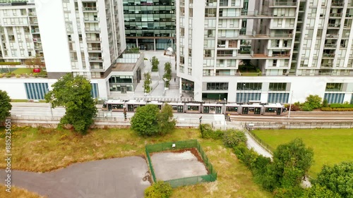 Aerial footage of contemporary apartment buildings with a tram passing by in Leopardstown, Dublin. The video showcases the vibrant urban setting with green spaces and modern architecture.