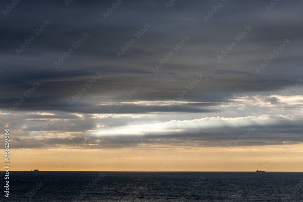 Sunset over the ocean with dramatic clouds, distant ship silhouettes, serene nature landscape at twilight Sunset over the ocean with dramatic clouds, distant ship silhouettes, serene nature landscape at twilight