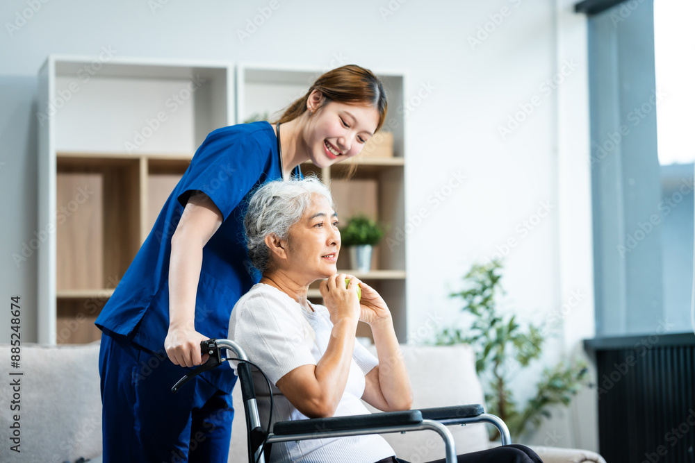A young Asian nurse, the only woman present, assists an older grey-haired mature woman on a wheelchair sitting on a sofa. They focus on taking a medical history and conducting health checks. A young Asian nurse, the only woman present, assists an older grey-haired mature woman on a wheelchair sitting on a sofa. They focus on taking a medical history and conducting health checks.