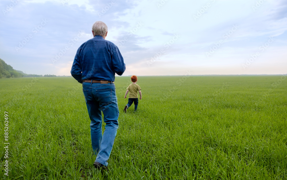 Senior man with grandson walking in field Senior man with grandson walking in field