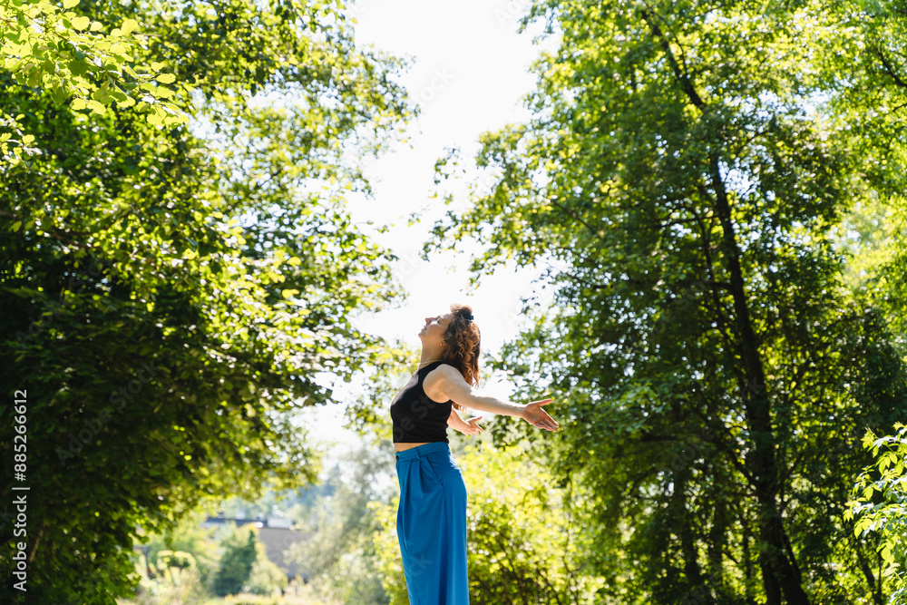 Carefree woman with arms outstretched standing in park Carefree woman with arms outstretched standing in park