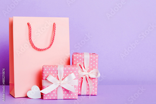 Shopping bag with gift box on colored background perspecrive view. Space for text holiday concept photo