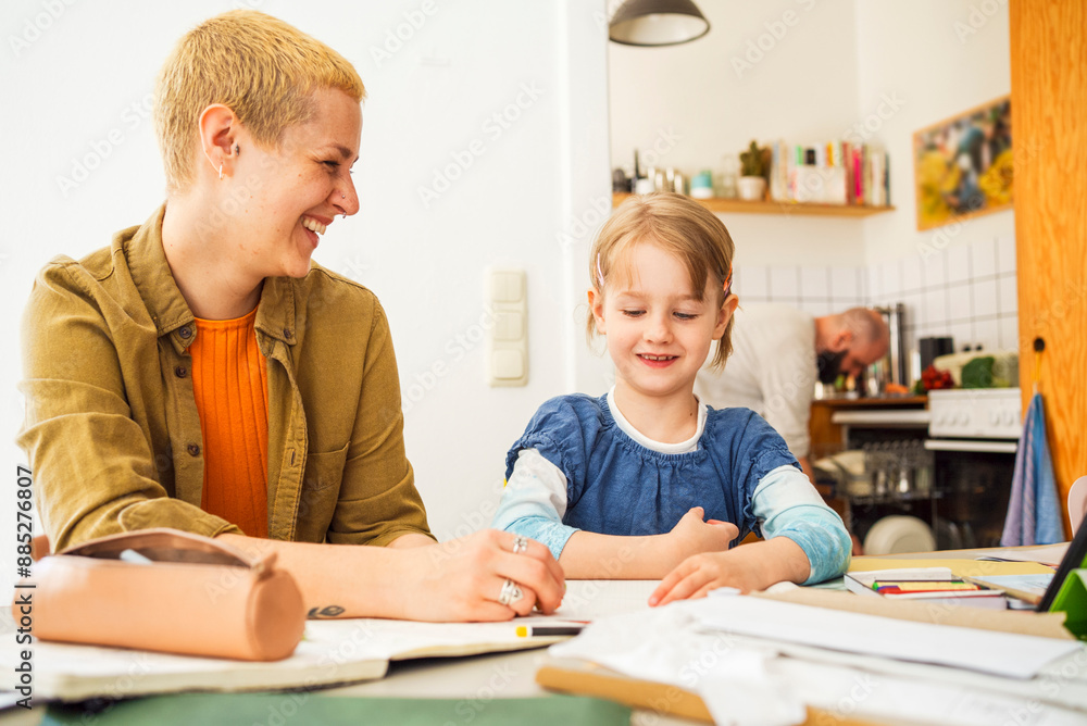 Smiling girl studying with mother at home Smiling girl studying with mother at home