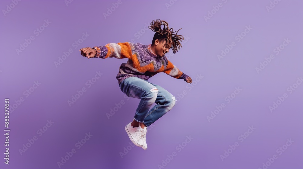 A teenager is captured mid-jump in a studio, wearing a colorful sweater and jeans. The teenager has a bright smile and exudes energy and happiness. The purple background adds a vibrant and playful A teenager is captured mid-jump in a studio, wearing a colorful sweater and jeans. The teenager has a bright smile and exudes energy and happiness. The purple background adds a vibrant and playful