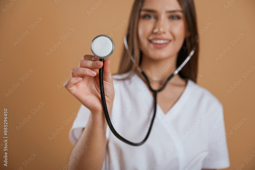 Stethoscope in hand. Young pretty woman is against background in the studio Stethoscope in hand. Young pretty woman is against background in the studio