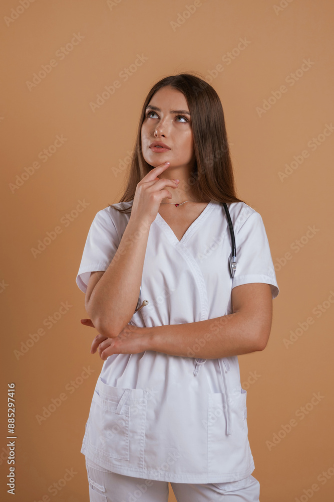 In doctor coat, with stethoscope. Young pretty woman is against background in the studio In doctor coat, with stethoscope. Young pretty woman is against background in the studio