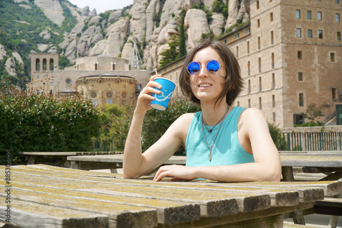 Obraz na płótnie Young woman tourist drinking a coffee on the grounds of Santa Maria Abbey in the mountains of Montserrat near Barcelona, Spain w salonie