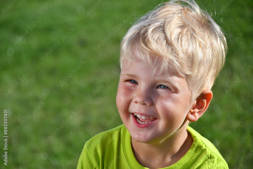 Close up portrait of positive smiling blond boy on natural grass background. Close up portrait of positive smiling blond boy on natural grass background.