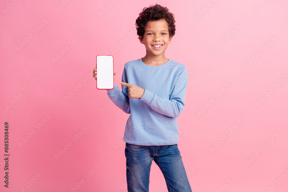 Photo of funky cool son dressed blue sweatshirt showing finger modern gadget emtpy space isolated pink color background Photo of funky cool son dressed blue sweatshirt showing finger modern gadget emtpy space isolated pink color background