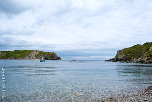 Lulworth cove bay from the beach. Small fisherman boats in the sea. Lulworth Cove bay and cliffs view . The Jurassic Coast is a World Heritage Site on the English Channel coast of southern England. photo