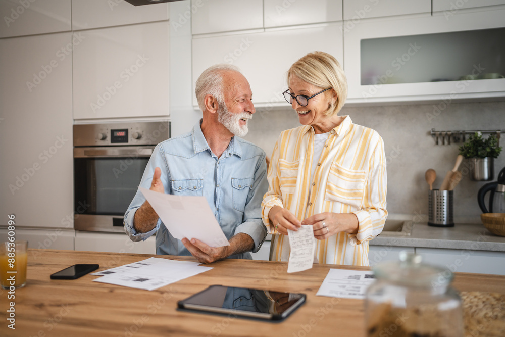 Senior couple read paper bills and invoice and discuss about payments Senior couple read paper bills and invoice and discuss about payments
