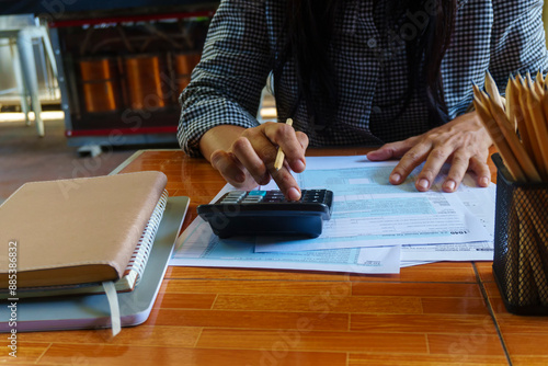 Business man use calculator, smartphone, and review tax form at home office. Financial advisor hand plan and calculate budget. Business and Financial Planning Concept.