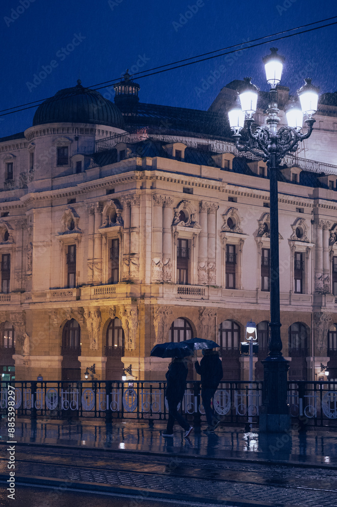 Naklejka premium Bilbao City at night with people with umbrellas