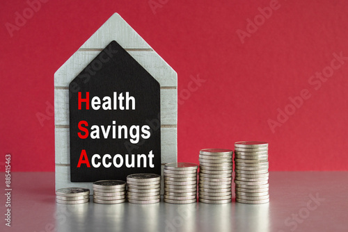 HSA health savings account symbol. Concept words 'HSA' on a black board. Silver coins arranged in a graph in front. Beautiful red background, grey table.  photo