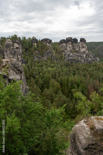 A mountain range with a forest in the background. The sky is cloudy and the trees are green