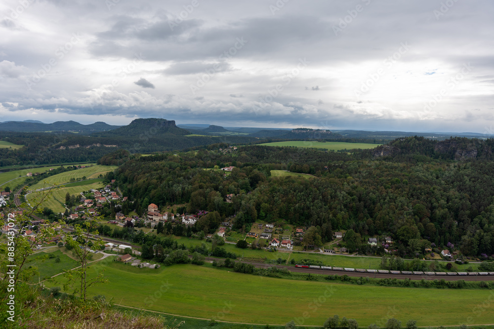 A rural area with a train passing through it. The train is in the foreground and the rest of the scene is mostly green A rural area with a train passing through it. The train is in the foreground and the rest of the scene is mostly green